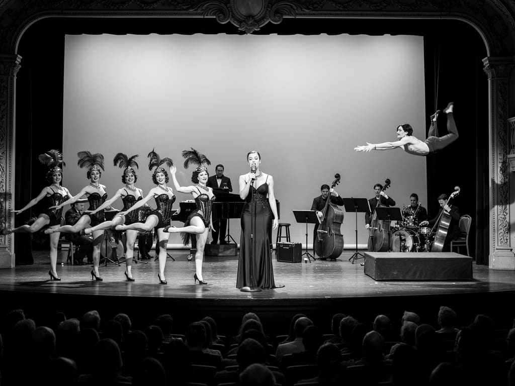 Danseurs, chanteuse, musiciens et acrobate sur la scène du cabaret